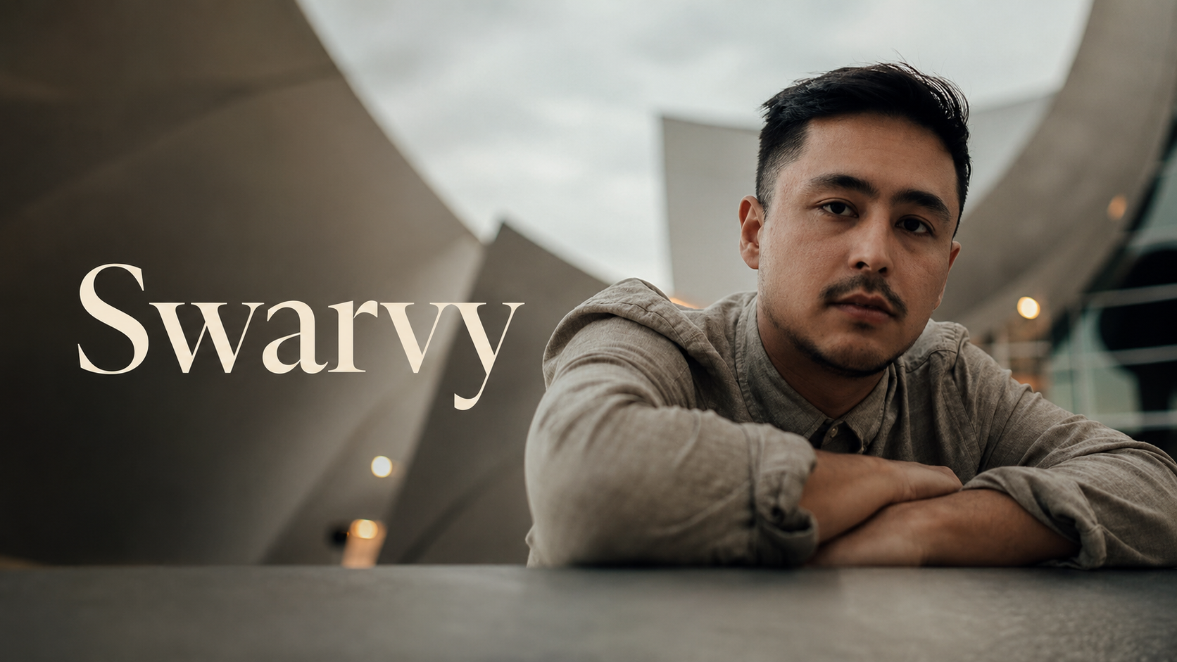 製作人 Swarvy 穿灰色襯衫趴在桌前的室內肖像