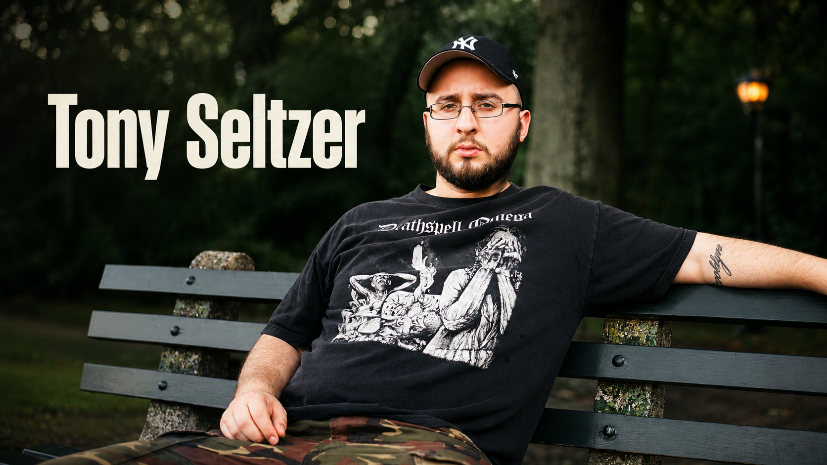 音樂人 Tony Seltzer 戴紐約洋基帽、坐在公園長椅上的肖像
