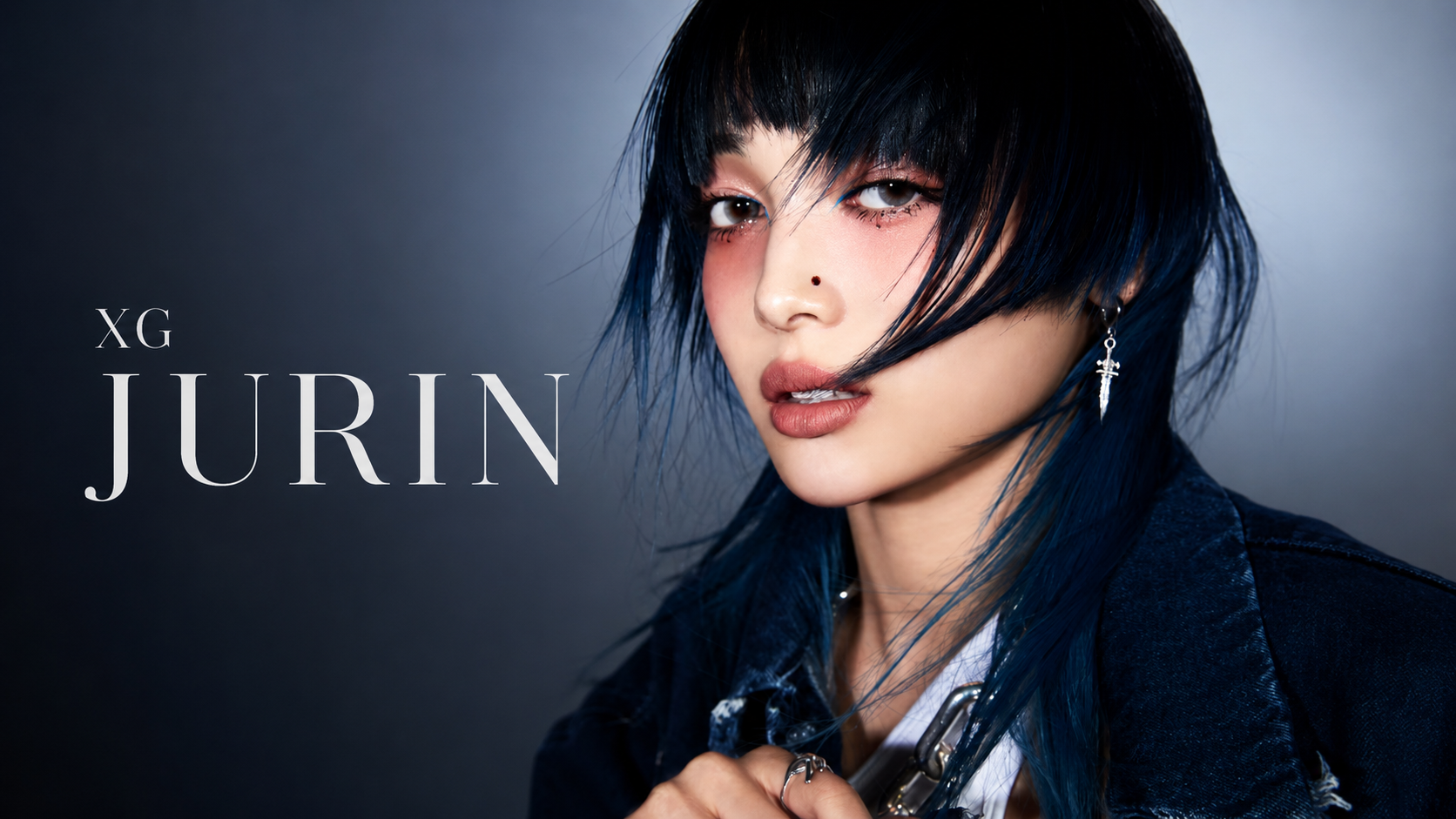 XG JURIN 宣傳肖像，藍黑短髮女性穿深色外套並直視鏡頭