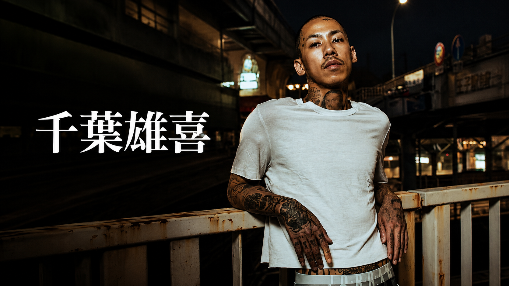 音樂人千葉雄喜穿白色 T 恤、站在夜間城市高架橋旁的肖像