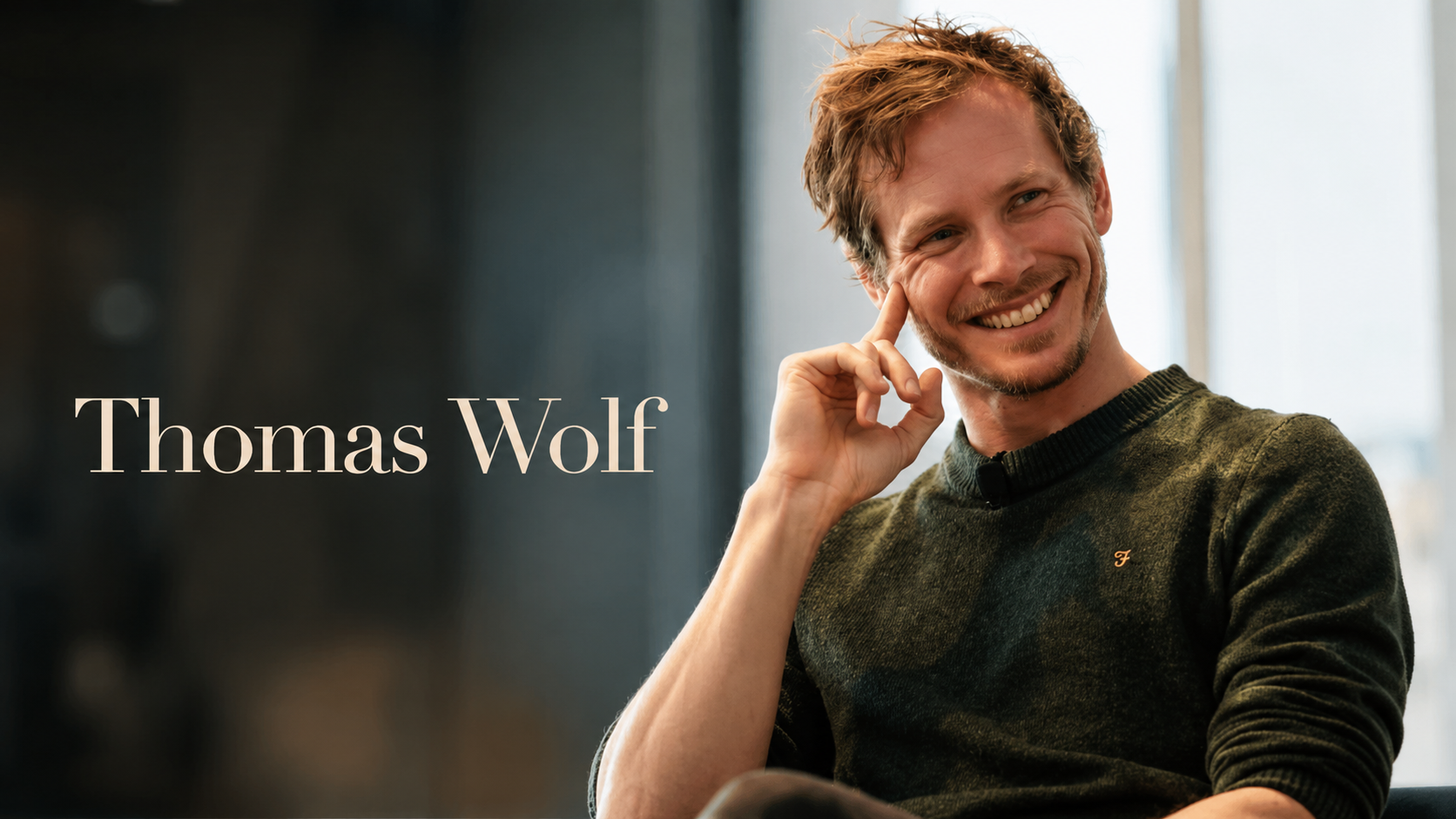 Thomas Wolf穿深綠色毛衣坐在室內，手指輕觸臉頰，畫面標示 Thomas Wolf