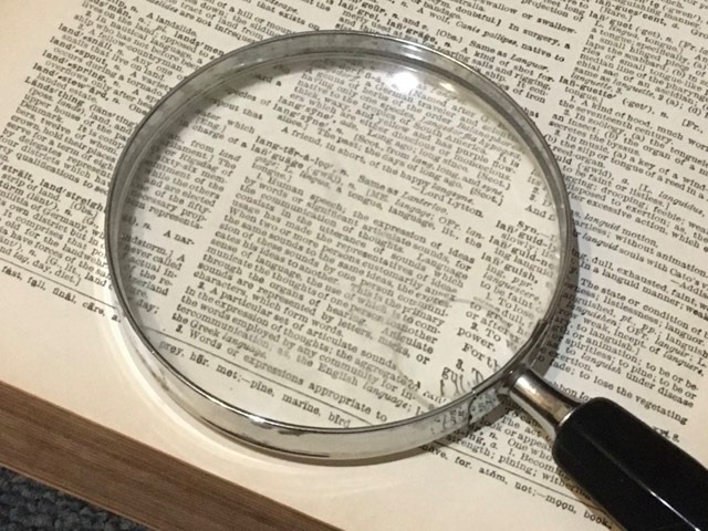 檢視書頁的放大鏡,象徵人物資料查證與來源邊界