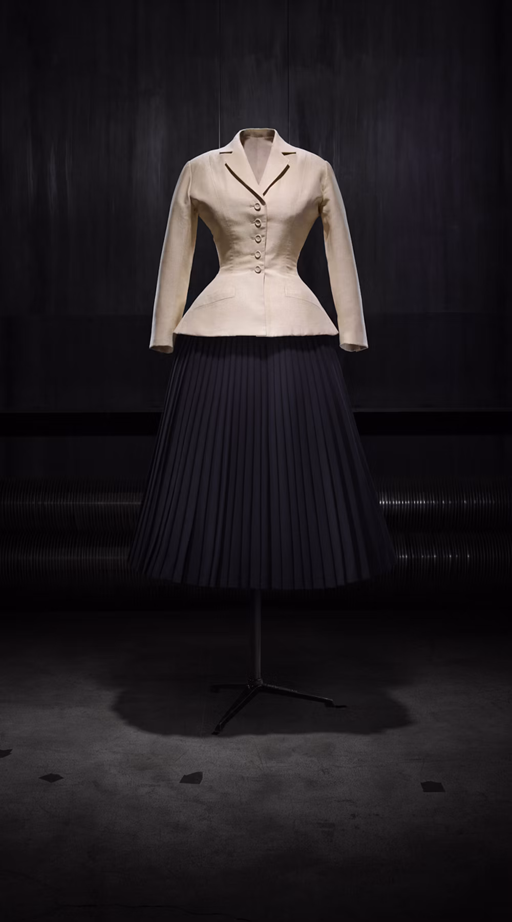 1947 年 Christian Dior Bar suit 的象牙色收腰外套與黑色百褶裙展示照